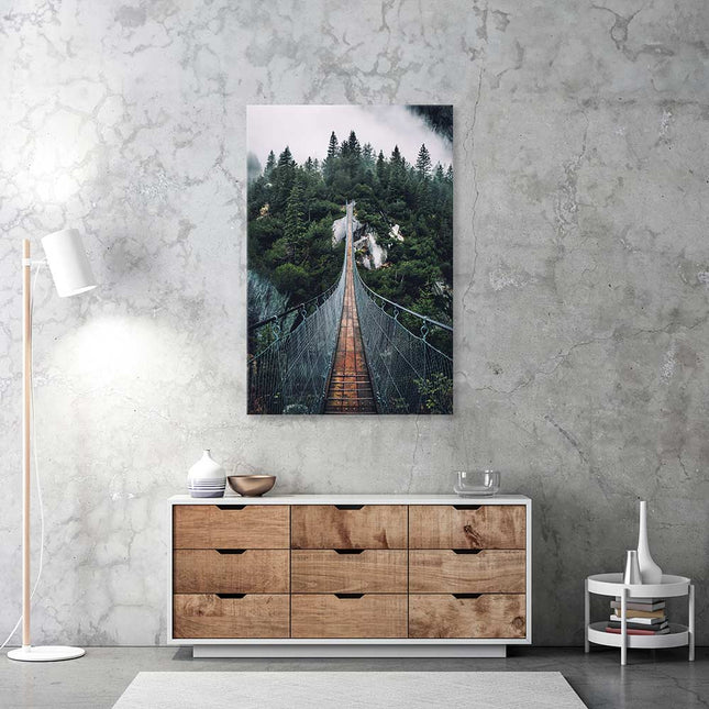 Leinwand bedruckt mit dem Foto einer Hängebrücke in der Schweiz. Es hängt an einer grauen Wand über einer Holzkommode.