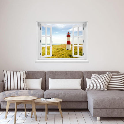Tauche ein in die Idylle der Ostsee in deinem eigenen Zuhause! Unser selbstklebendes Wandbild mit Leuchtturm bietet eine entspannende Aussicht auf die Dünen und das ruhige Meer, angebracht an der Wand über einer grauen Couch.