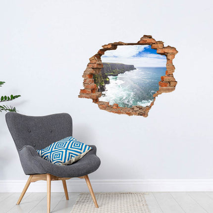 Wandaufkleber Wandtattoo in Form eines Wanddurchbruchs mit Atlantikküste als Hauptbild mit grauem Sessel 