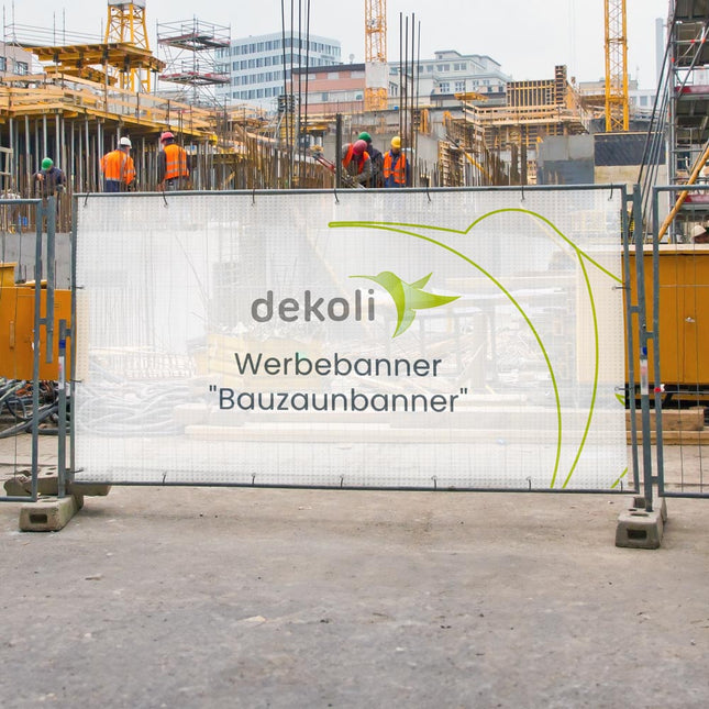 Werbebanner von dekoli mit der Aufschrift "Bauzaunbanner", angebracht an einem Bauzaun vor einer belebten Baustelle, effektiv für Branding und Sichtbarkeit in urbanen Bauprojekten.
