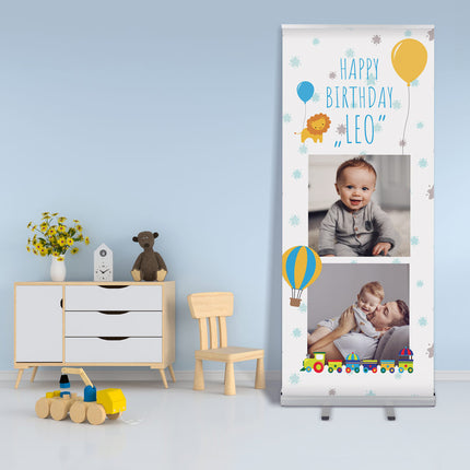 Personalisiertes Roll-Up Banner für Kindergeburtstag mit 'Happy Birthday Leo' Schriftzug, Ballons und Fotos, in einem Kinderzimmer dekoriert.