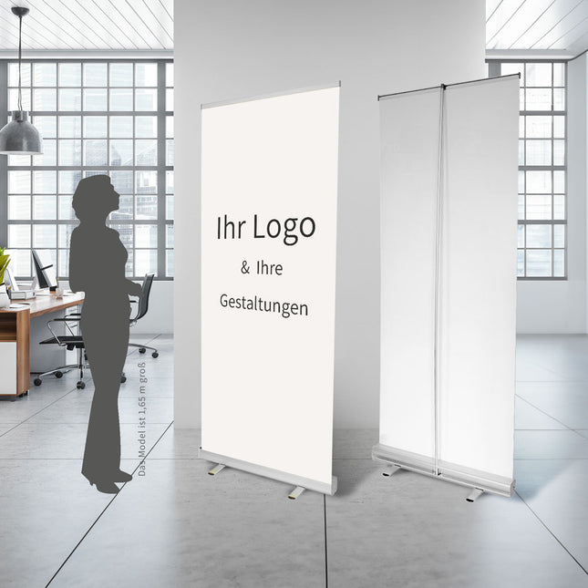 Personalisierbare Roll-Up Banner im Büro, anpassbar mit Ihrem Logo & Design, illustriert neben einer weiblichen Silhouette zur Visualisierung der Größenverhältnisse.