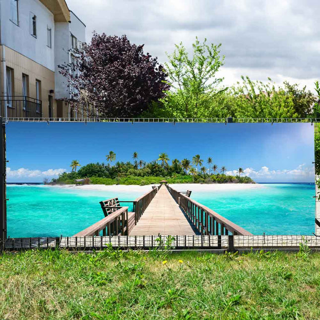 Farbintensiver Zaunbanner als Sichtschutz für Zaun und Balkongeländer mit Motiv Insel, Steg und türkisblauem Meer.