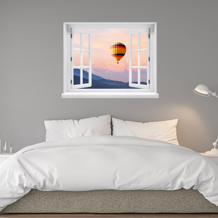 Genießen Sie den Charme eines Bergpanoramas daheim! Selbstklebendes Fenstermotiv mit Sonnenuntergang und Heißluftballon, als Aussicht über einem Bett an einer grauen Schlafzimmerwand.