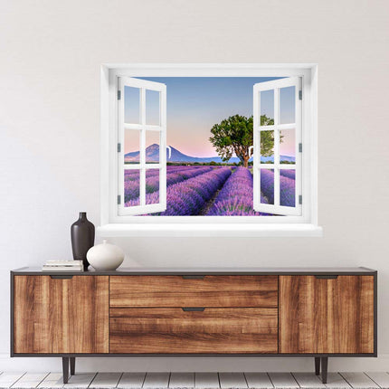 Bringen Sie das südfranzösische Urlaubsfeeling nach Hause! Selbstklebendes Wandbild mit Fenstermotiv und malerischer Aussicht auf ein Lavendelfeld vor einer atemberaubenden Bergkulisse in der Provence, aufgehangen über einer Kommode im Wohnzimmer.