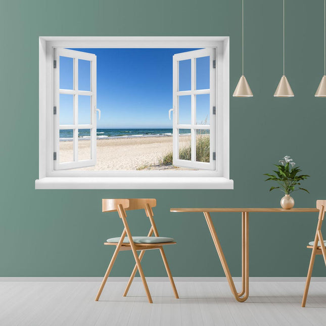 Wandmotiv mit idyllischem Fensterausblick auf einen Ostseestrand, mit strahlend blauem Himmel, als Dekoration an einer grünen Wand neben einem Esstisch.
